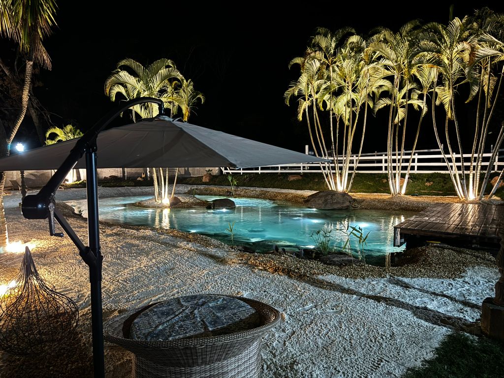 Piscina natural iluminada à noite — projeto tratado com tecnologia Purity Tech